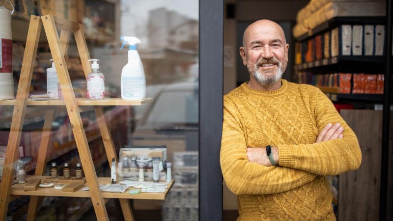 small business owner standing in front of storefront 